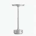 Minimalist cordless rechargeable table lamp in brushed aluminum, featuring a slender stand and a sleek, circular light head, shown against a solid white background.
